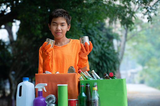Asian boy is separating bottles, plastic bags, food containers at home,  soft and selective focus, eco friends and environment care concept.