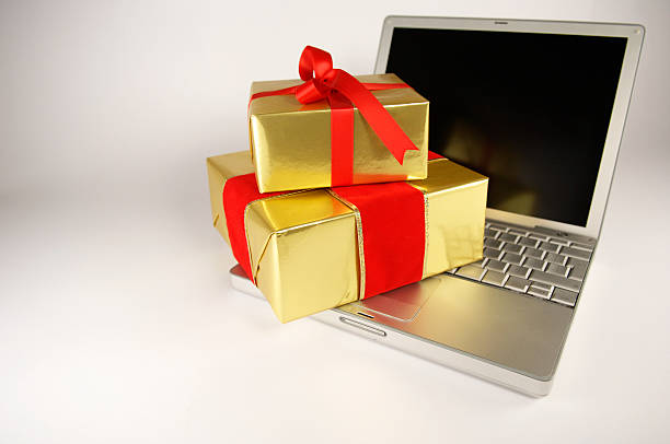 istock Two gold wrapped gifts sitting on a laptop on white back. 180700458