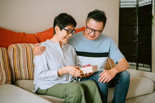 Young man giving  gift to his mother.