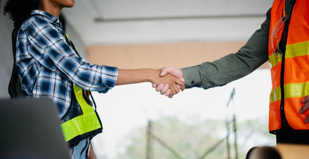 istock Construction team shake hands greeting start new project plan behind yellow helmet in office center to consults about their building project. 1807018589