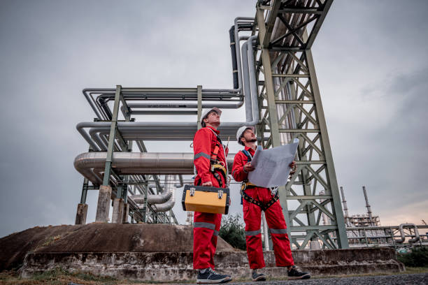 istock Engineer survey team wear uniform and helmet stand workplace checking blueprint project , radio communication and engineer box inspection work construction site with oil refinery background. 1807030471