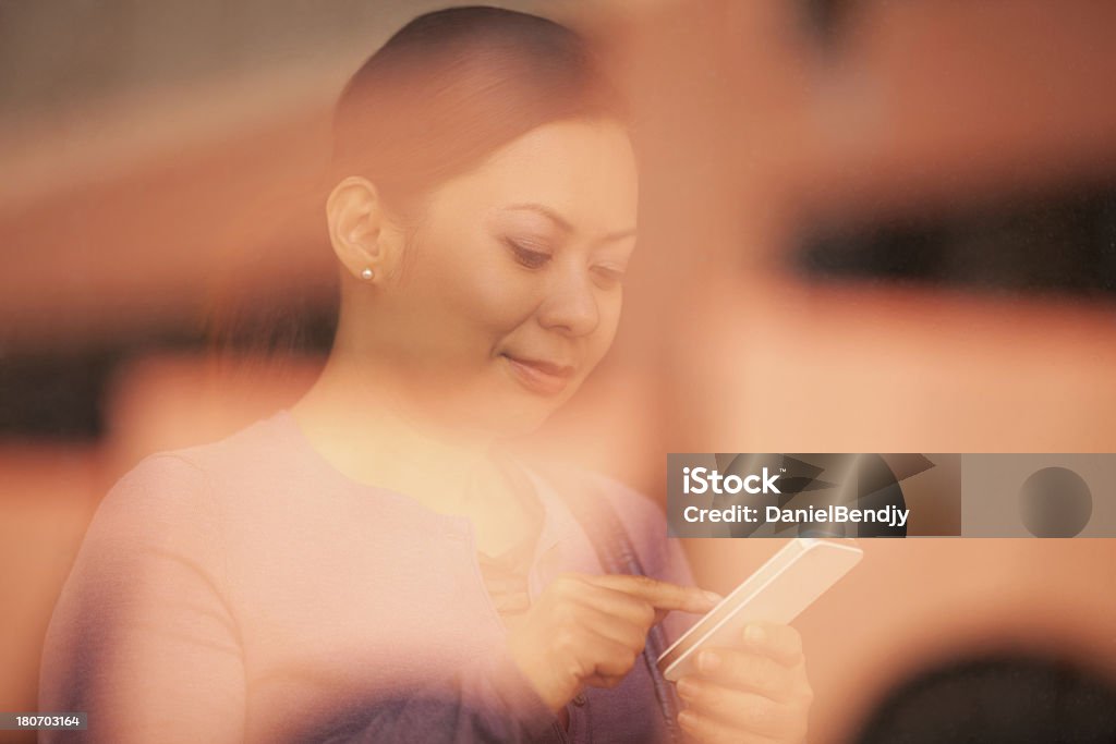 Femme asiatique à l'aide de téléphone intelligent derrière une fenêtre - Photo de Adulte libre de droits