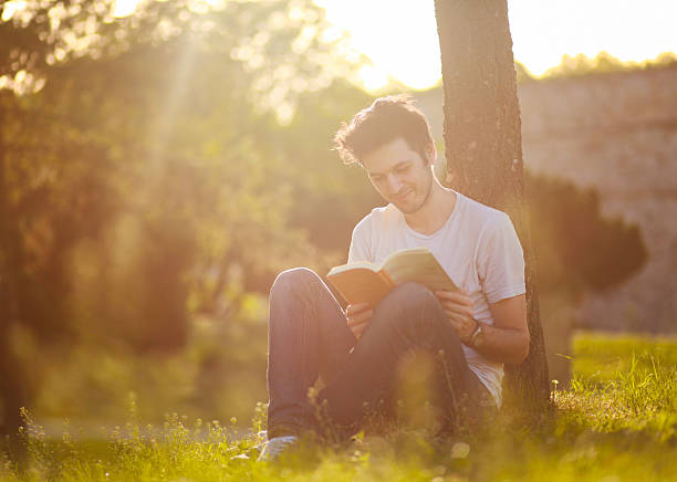istock Young man reading a book in the summer nature 180703213