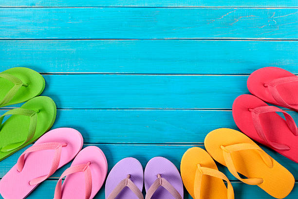 istock Colorful flip flops atop blue wooden deck 180703538