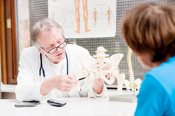 Orthopedist talking to a patient "A mature orthopedist, explaining the problems of the hip to a patient. XXL size image." pain points stock pictures, royalty-free photos & images