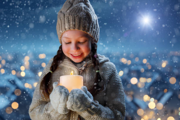 Adorable little girl with candle on Christmas outdoors.