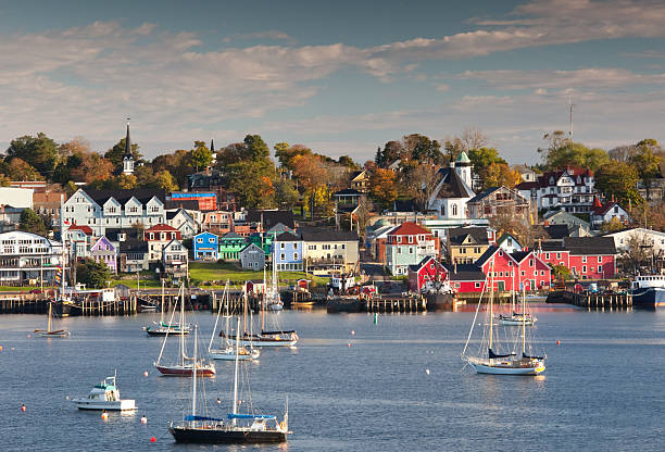 Waterfront view of Lunenburg Nova Scotia in the fall. The beautiful and historic town of Lunenburg, Nova Scotia in the fall. Boats drift in the harbour and the amazing colours of the buildings in this picturesque seaside town add to the scene. This image was taken across the harbour from town on a gorgeous fall morning. Lunenburg is located approximately an hour from Halifax.  maritime provinces stock pictures, royalty-free photos & images