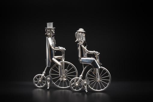 Metal figures of a gentleman and a lady riding retro bicycles