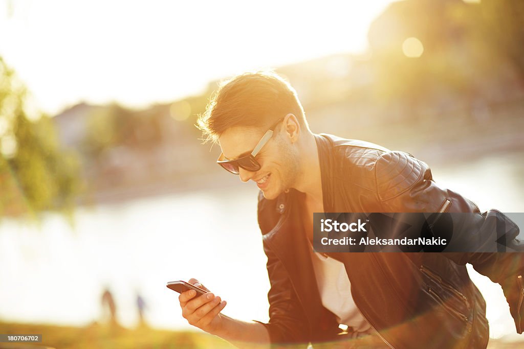 Sonriente hombre usando un teléfono inteligente al aire libre - Foto de stock de 20 a 29 años libre de derechos