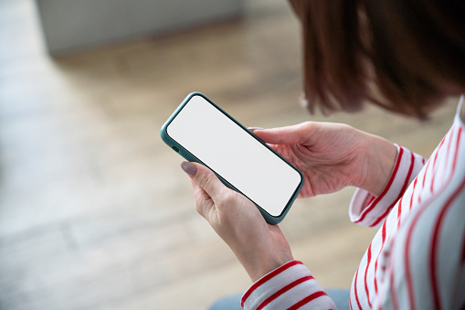 Woman uses a smartphone with a blank white screen indoors