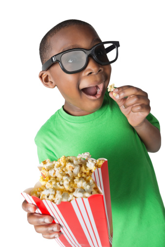 Excited boy eating popcorn wearing 3D glasses; studio shot