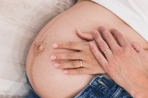 Close up of a Man touching pregnant woman's belly indoors.