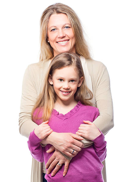 young mother hugging her child outdoors, woman and a teenage girl in a white dress on a green background of a summer field, Happy family