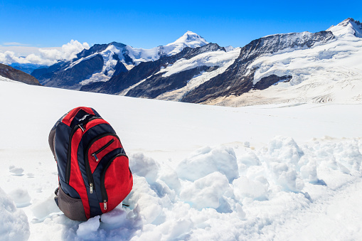Tourist backpack on a snow on background of mountains in Swiss Alps. Travel outdoor concept