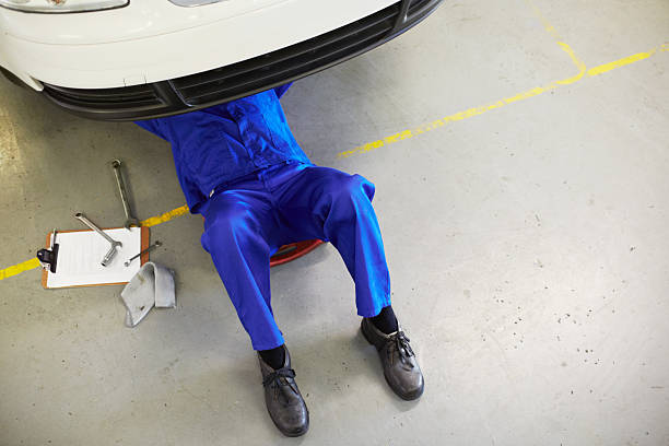 Getting the job done right Top view of a mechanic on his back and working on the undercarriage of car - copyspace car mechanic top view stock pictures, royalty-free photos & images