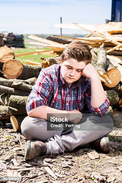 Foto de Triste Garoto Sentado Sozinho Ao Lado De Uma Exploração Agrícola Pilha De Lenha e mais fotos de stock de 14-15 Anos