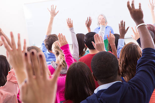 istock College students raising hands in crowded lecture hall 180708802