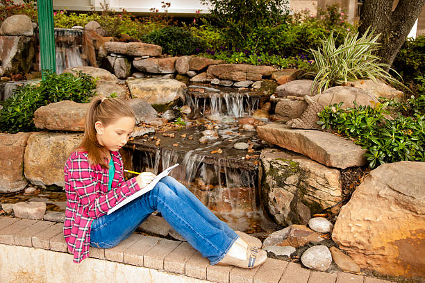 niños: hermosa chica primaria escribiendo en el cuaderno de la cascada. - diary student lovelocal elementary age fotografías e imágenes de stock