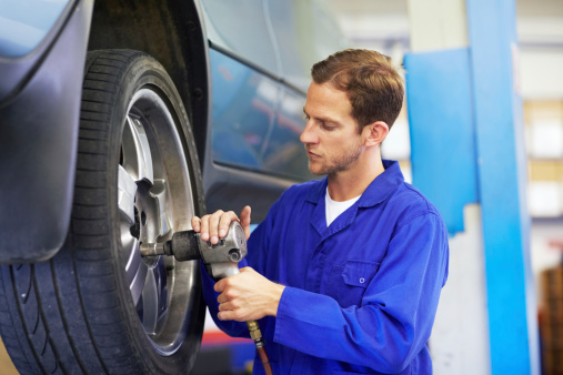 A mechanic torquing the lug nuts of a wheel with a wrench