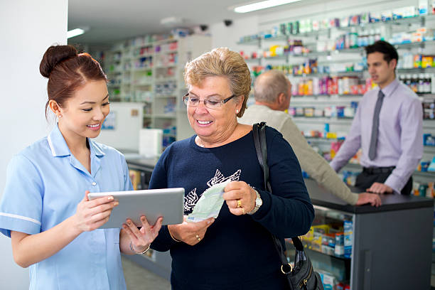 tableta digital en la farmacia - pharmacist mature adult smiling senior adult fotografías e imágenes de stock