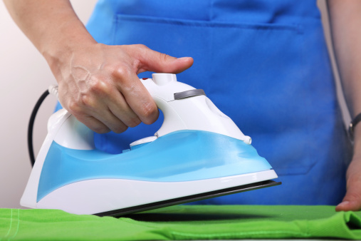 Woman in blue apron ironing a green shirtOther relates images: