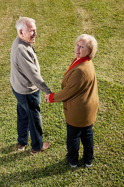 coppia senior tenendo le mani - looking over shoulder looking men looking up foto e immagini stock