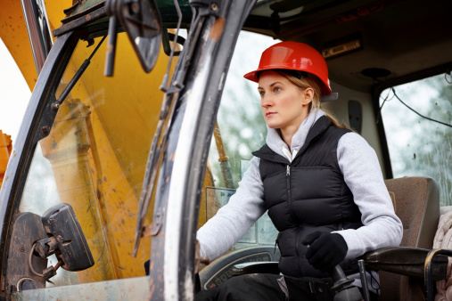 Female construction worker driving an earth mover on a construction site
