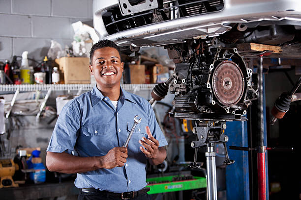 Auto mechanic fixing car transmission African American auto mechanic (30s) repairing a car, working on the transmission. car mechanic top view stock pictures, royalty-free photos & images