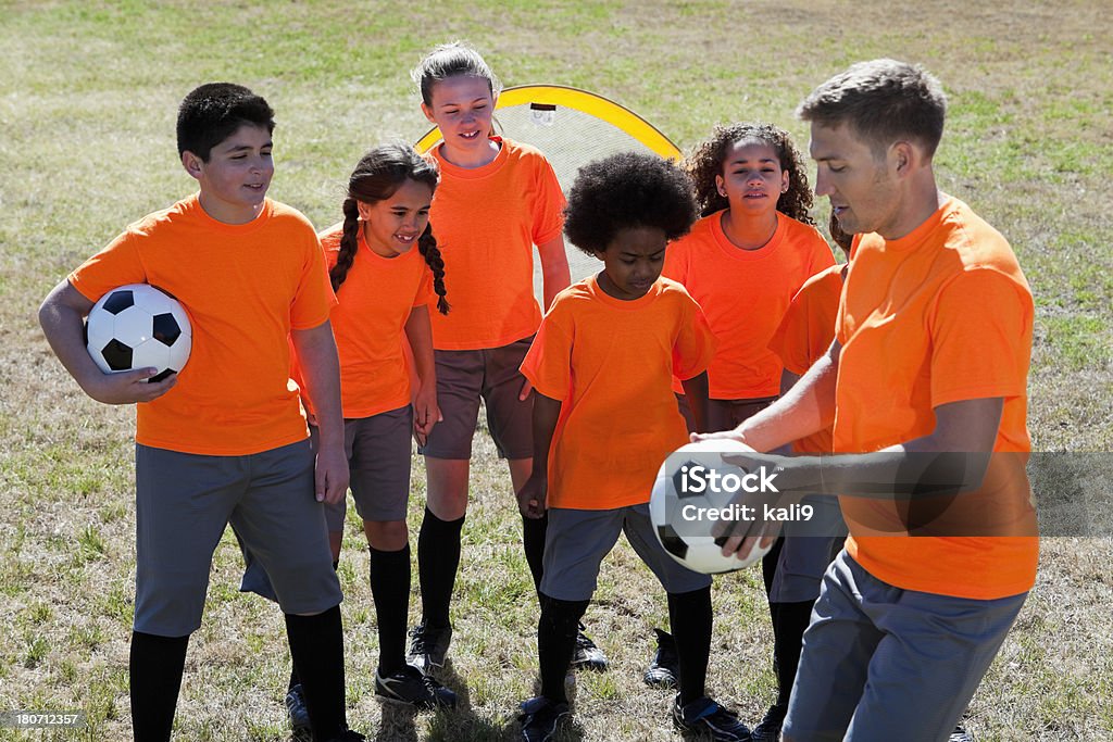 Entraîneur avec les enfants pratiquant le football - Photo de 10-11 ans libre de droits