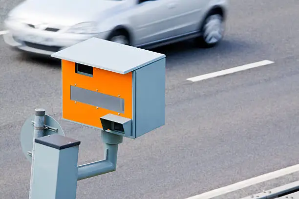 A UK GATSO speed camera monitors the speed of a passing car.Motion blur on car. Good copy space.