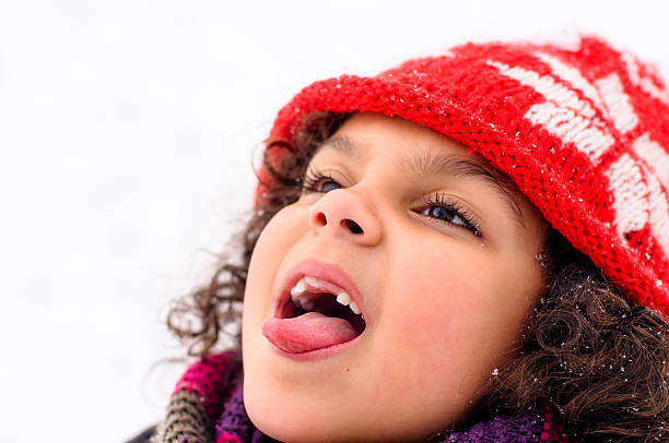 Royalty free stock photo of 6 years old girl trying to taste the falling snow.