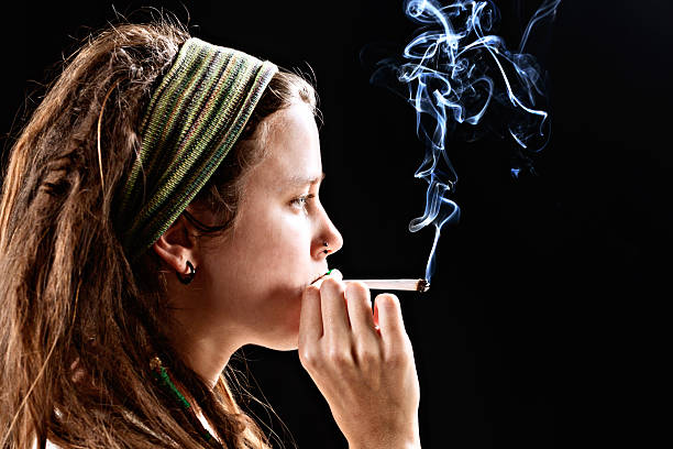 istock Serious young woman puffs on a marijuana reefer 180713117