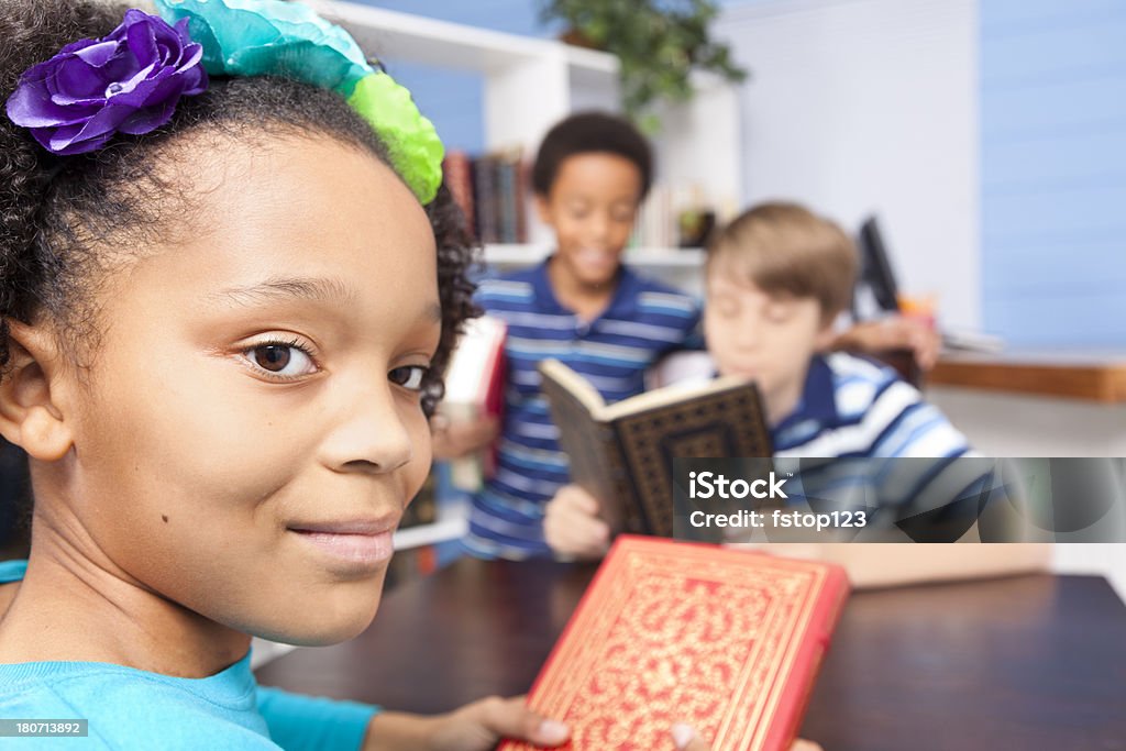 Educação: Multi étnica alunos junior elevado na biblioteca. Ler a tabela. - Royalty-free 10-11 Anos Foto de stock