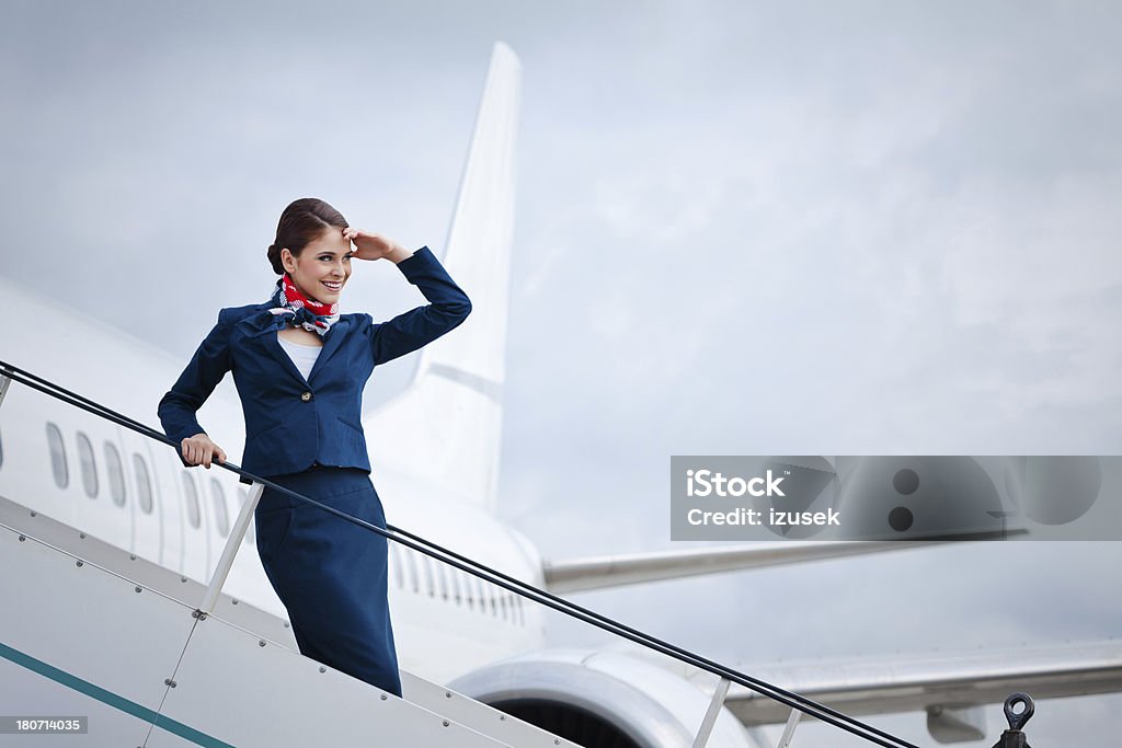 Before the flight "Outdoor portrait of a beautiful flight attendant standing on the aircraft stairs, waiting for travellers." Air Stewardess Stock Photo