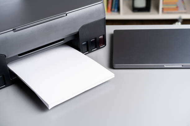 istock Printer and laptop on grey table in office 1807147469