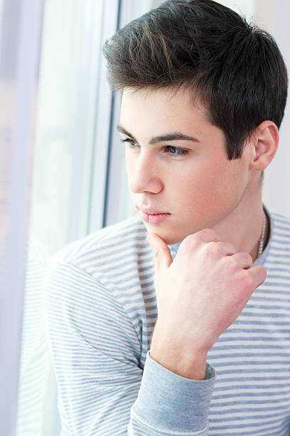 istock Portrait of smart young guy looking at window 180714826