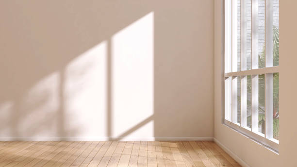 istock Blank cream wall in empty room in sunlight from white frame window on brown parquet floor to courtyard with tree 1807148493