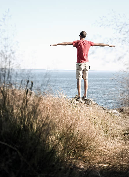 Letting go A man with no cares in the world takes in the scenery before him on the rocky coasts of Quoddy Head State Park. Adventure and exploration. quoddy head state park stock pictures, royalty-free photos & images