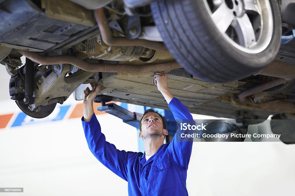Here's the problem! A diligent mechanic inspecting the undercarriage of a car Adult Stock Photo
