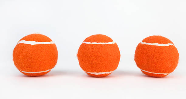 Tennis Balls Three orange tennis balls with white stripes. Horizontal. tennis ball container stock pictures, royalty-free photos & images