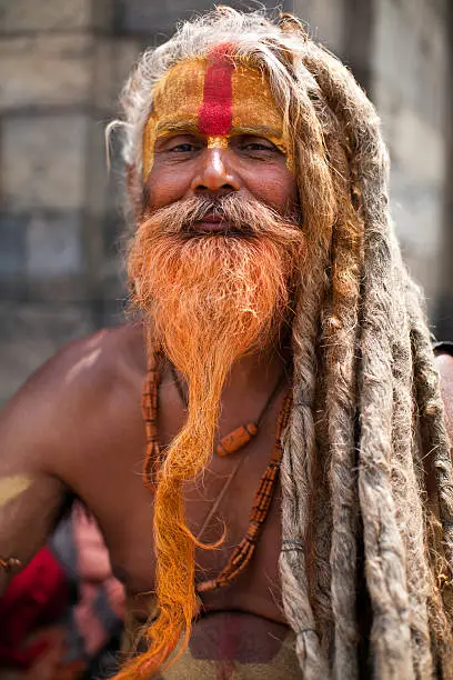 "Portrait of Holy Sadhu man with long beard and traditional face paint in Pashupatinath Temple, Kathamandu, Nepal."