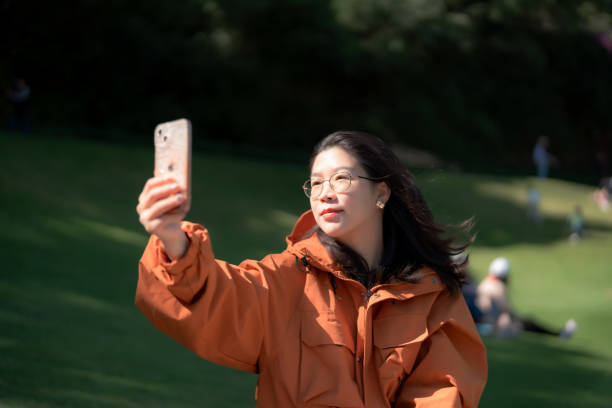 istock Asian lady taking selfie with mobile phone on grass 1807179610