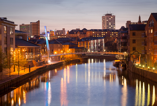Long exposure shot of River Aire in the centre of Leeds at night. The photo shows the Centenary footbridge and the area known as Brewery Wharf, which is has been redeveloped and is populated with restaurants, hotels, bars, shops and apartments.