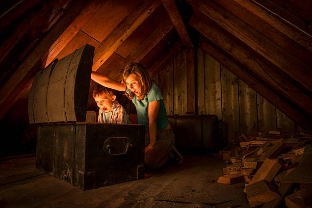 kids finding a treasure chest at the attic two surprised kids opening a glowing treasure chest at the attic of an old house treasure chest photos stock pictures, royalty-free photos & images