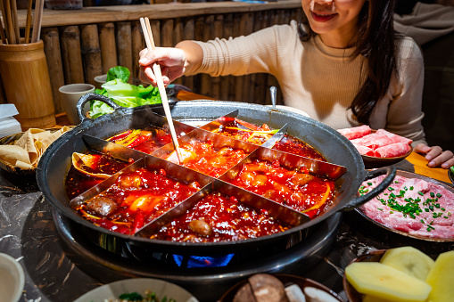 Female tourist eating original mala spicy hot pot in Chongqing, China