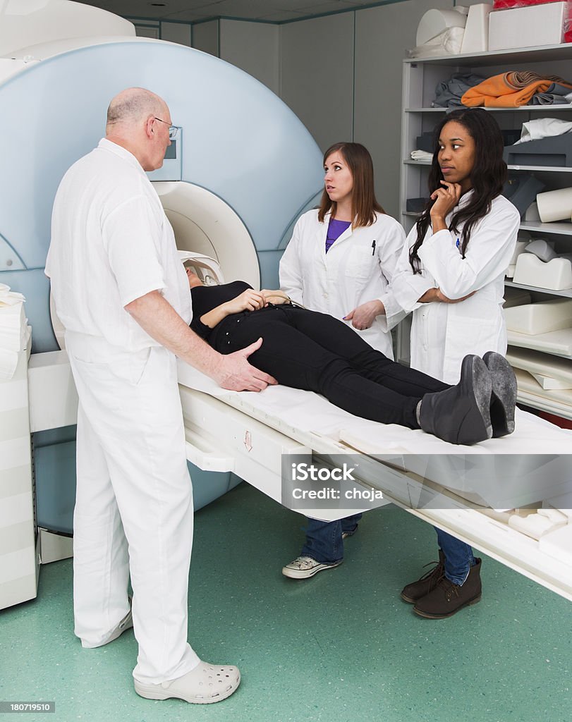 Mulher doente s'Exame de ressonância magnética, auxiliar de chefe Radiologista, dois médicos - Foto de stock de Exame de ressonância magnética royalty-free