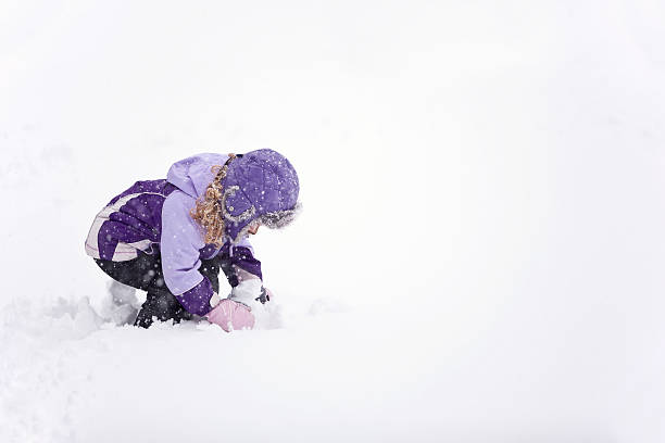 Side view of a young girl playing in the snow.