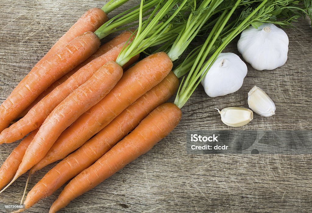 Świeże marchewki i czosnek na starej desce do krojenia - Zbiór zdjęć royalty-free (Bez ludzi)
