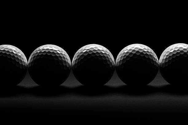 A moody studio shot, with a golf ball on a tee spotlit from above casting shadows