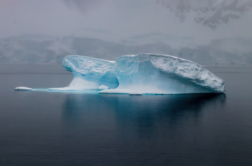 Iceberg in dead calm water near the AntaRctic Peninsula. Blue ice; reflection on water.
